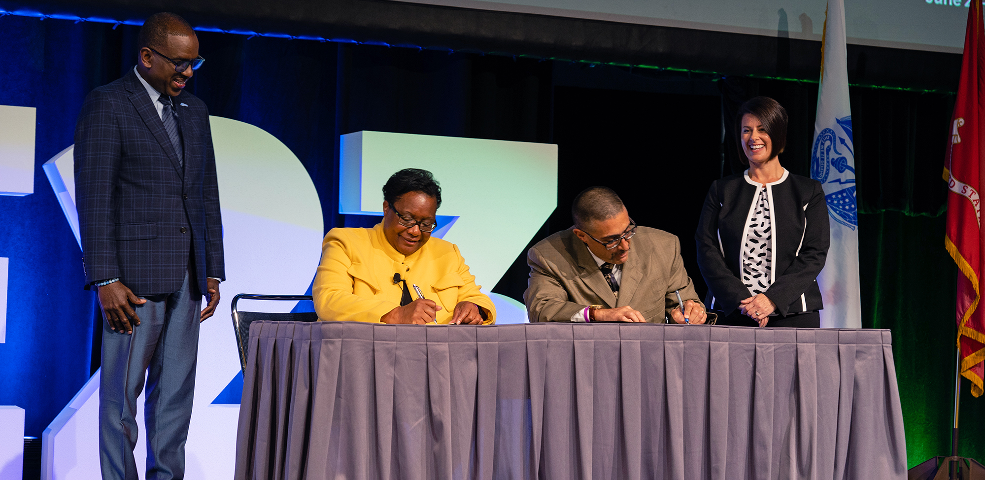 Carolyn Hardin, Chief of Training and Research at All Rise, left center, signs the MOU with NTCAA Chair Carlos Gonzales, right center, as Terrence Walton, All Rise COO, left, and Abby Frutchey, NTCAA vice chair and All Rise board member, right, look on.